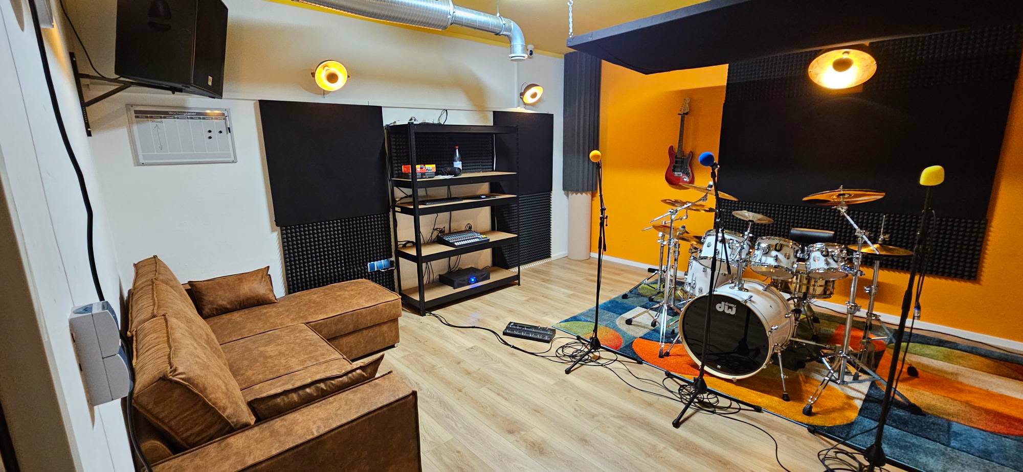 Proberaum mit Sofa, analogem Mixer und Schlagzeug