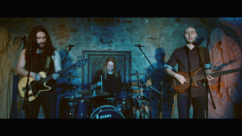 120 Minds mit Gitarre, Bass und Schlagzeug vor einer blau beleuchteten Steinwand